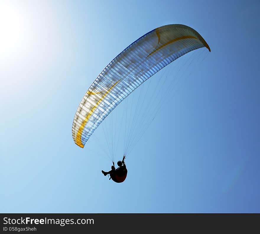 Silhouette of paraglider against the blue sky