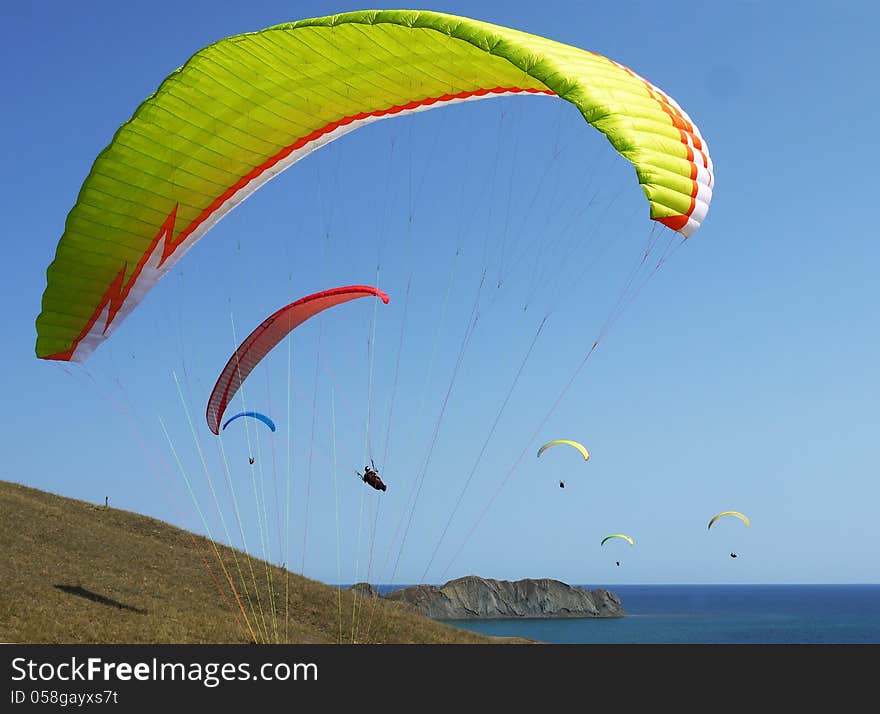 Few paragliders soar over the sea shore