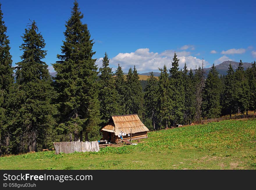 Wooden house shepherds in the mountains. Summer landscape with blue sky. Wooden house shepherds in the mountains. Summer landscape with blue sky