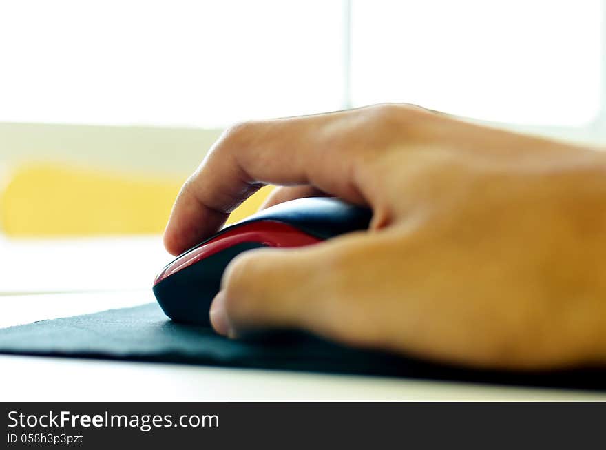 Hand using a computer mouse on a table.