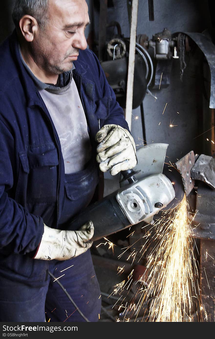 Heavy industry worker cutting steel plate with grinder in workshop. Heavy industry worker cutting steel plate with grinder in workshop.