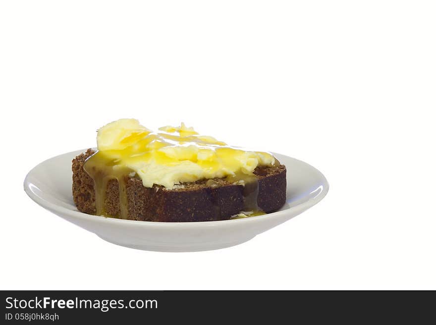 A piece of rye bread with butter and honey on a saucer, isolated on white