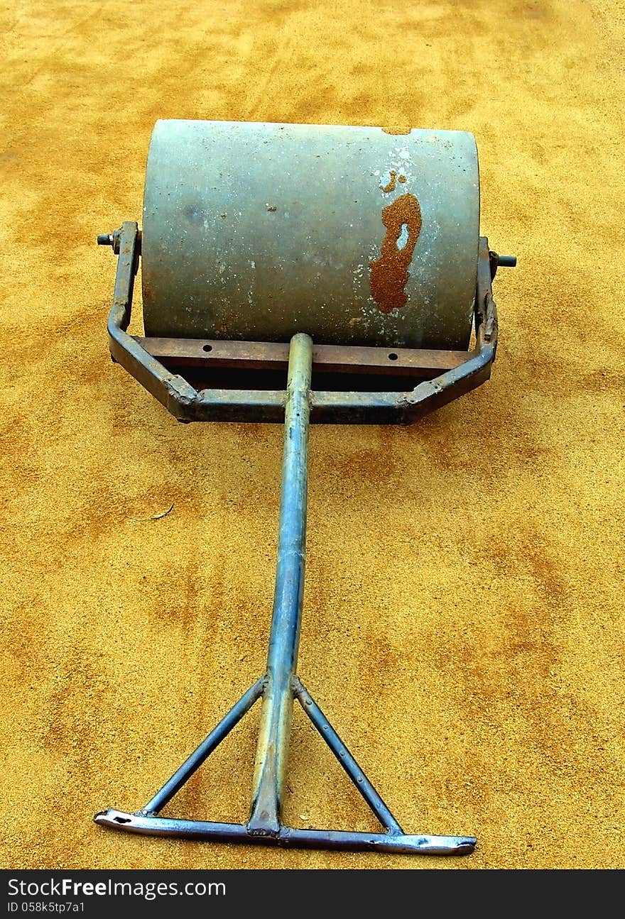 A manual steamroller on a tennis court.