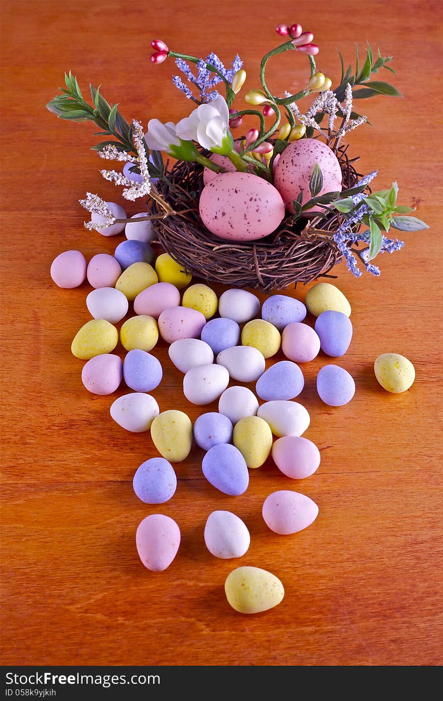 Easter eggs in nest and candies on a wooden background. Easter eggs in nest and candies on a wooden background