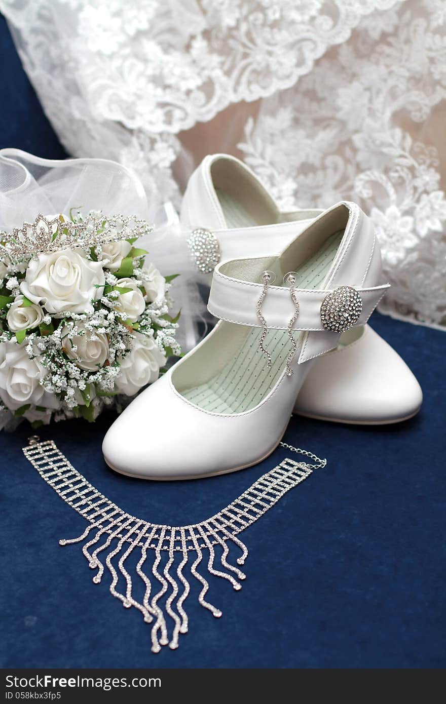 White bridal bouquet, white shoes, necklace and earrings on blue velvet. White bridal bouquet, white shoes, necklace and earrings on blue velvet