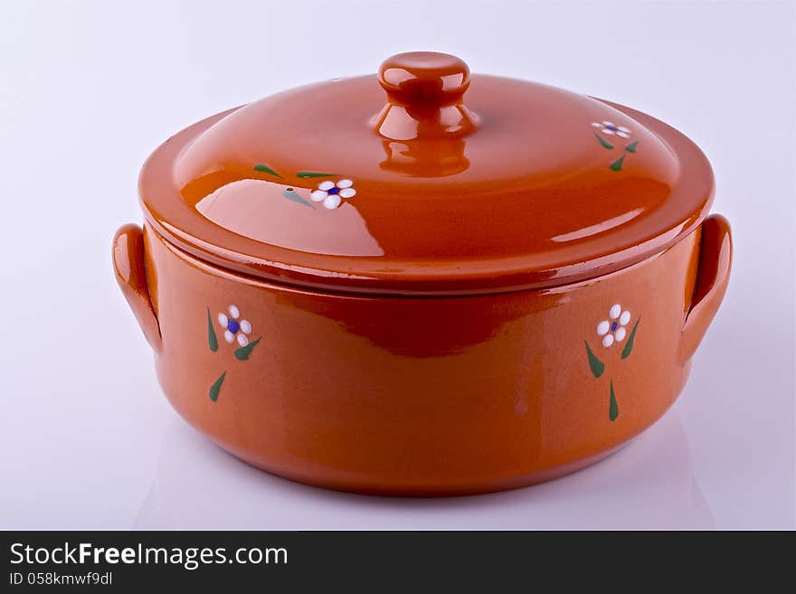 Orange ceramic clay pot with lid on a light background