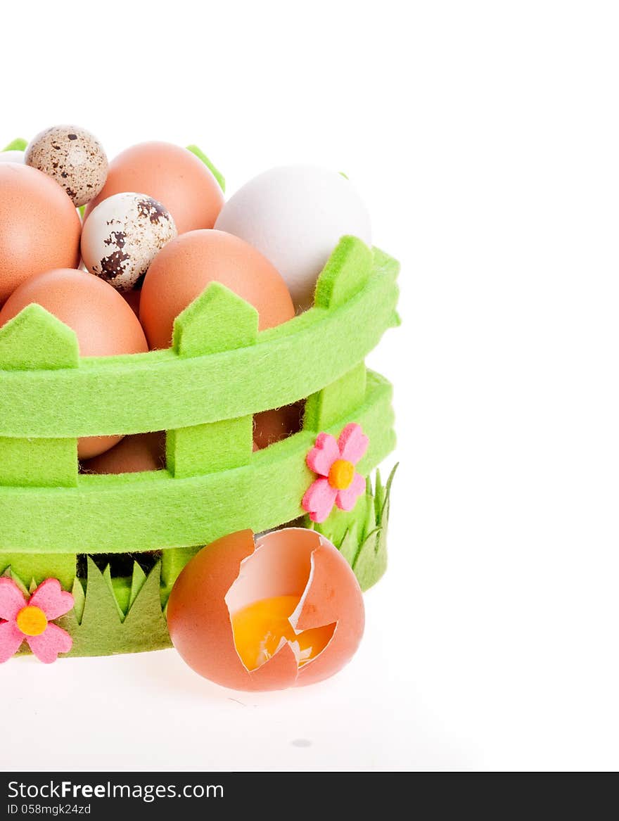 Broken chicken egg lies near a decorative basket of eggs