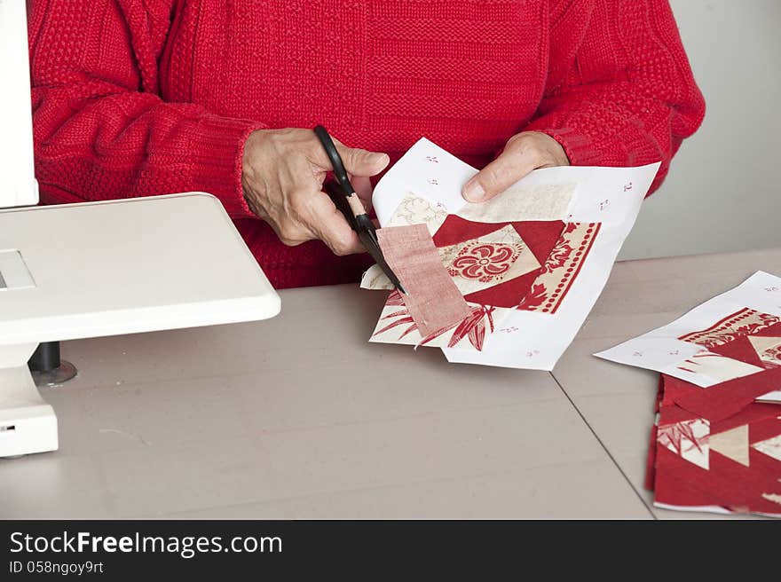 A quilter cuts off excess material for accurate seam allowance of a quilt block. A quilter cuts off excess material for accurate seam allowance of a quilt block.