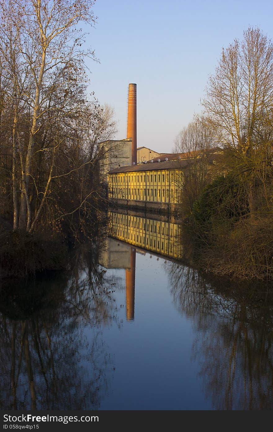 An old factory near a river, with beautiful reflection. An old factory near a river, with beautiful reflection