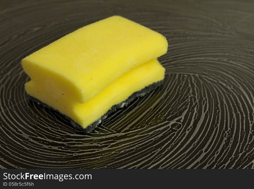 Cleaning sponge with white foam laying on black glassy stove