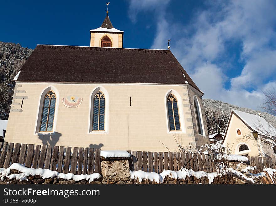 A wintertime view of a small church with a tall steeple