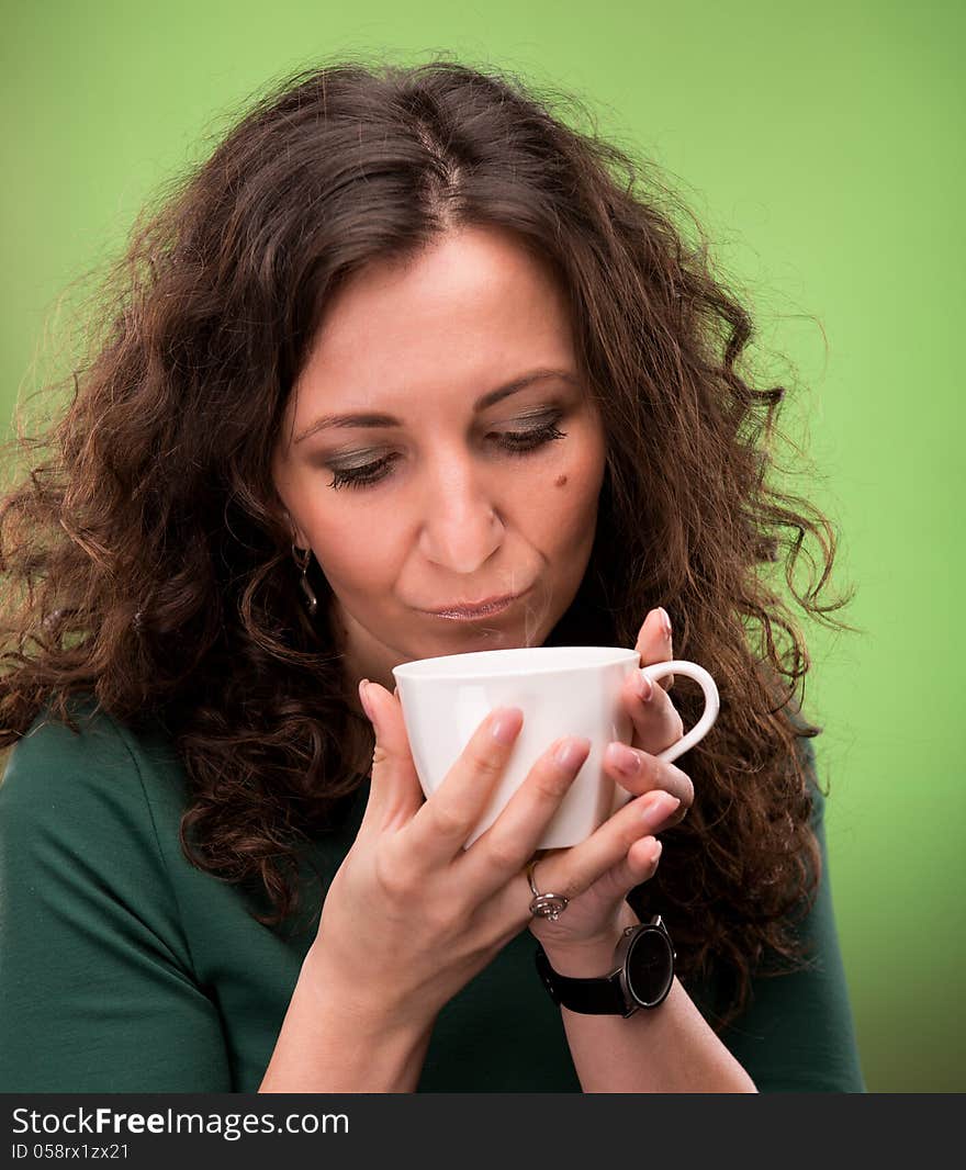 Curly woman with a cup of tea or coffee on a green background