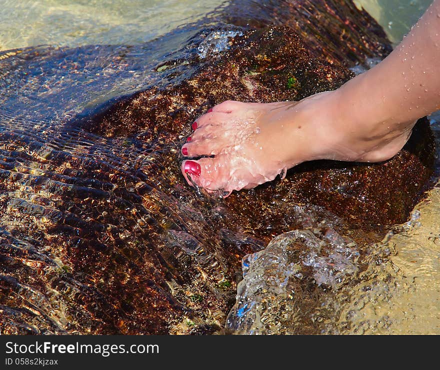 Woman's foot on the beach rock in the water. Woman's foot on the beach rock in the water