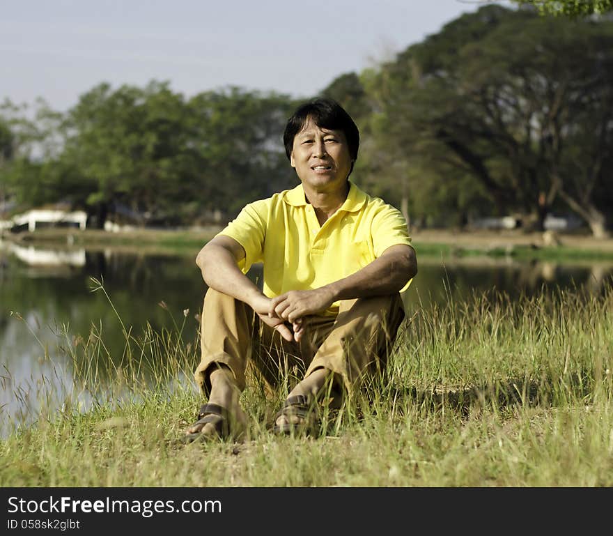 Asian Man Sitting  In The Park