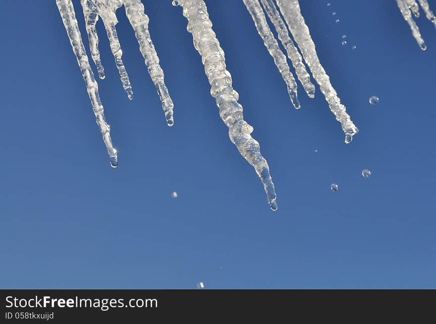 Icicles, water drops and bright, blue sky