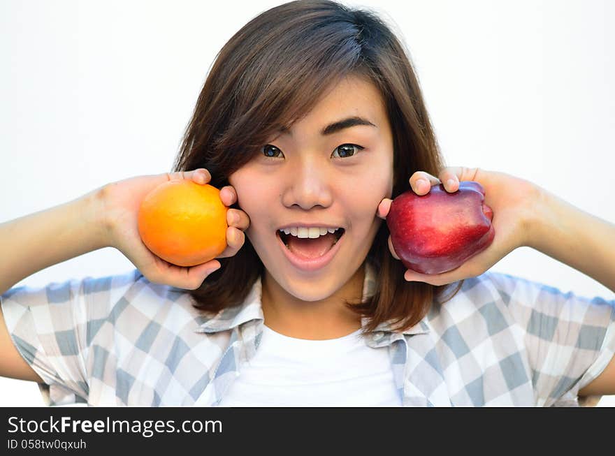 Beautiful asian teenage holding orange and apple fruits near smi