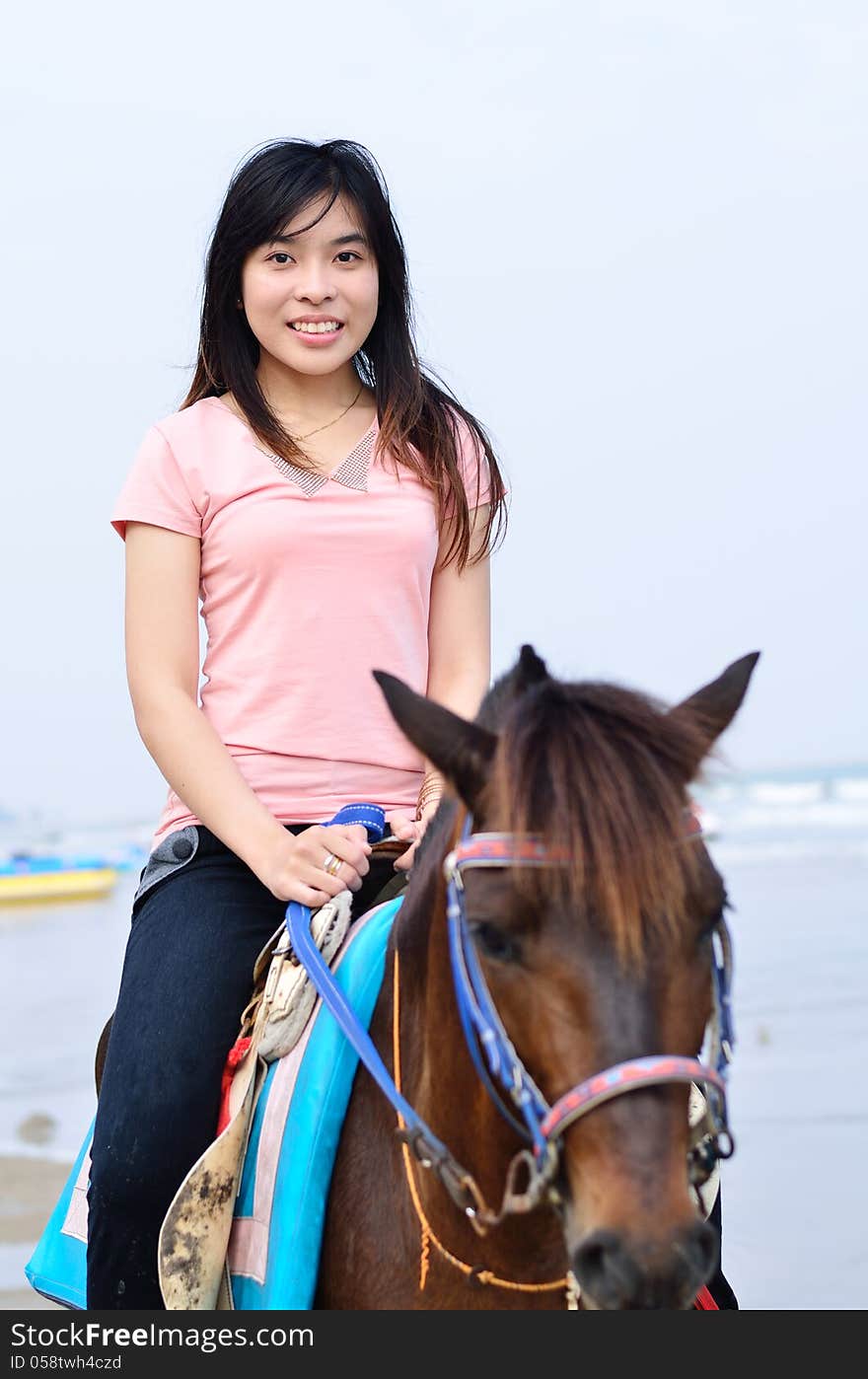 Beautiful asian woman with brown horse on beach