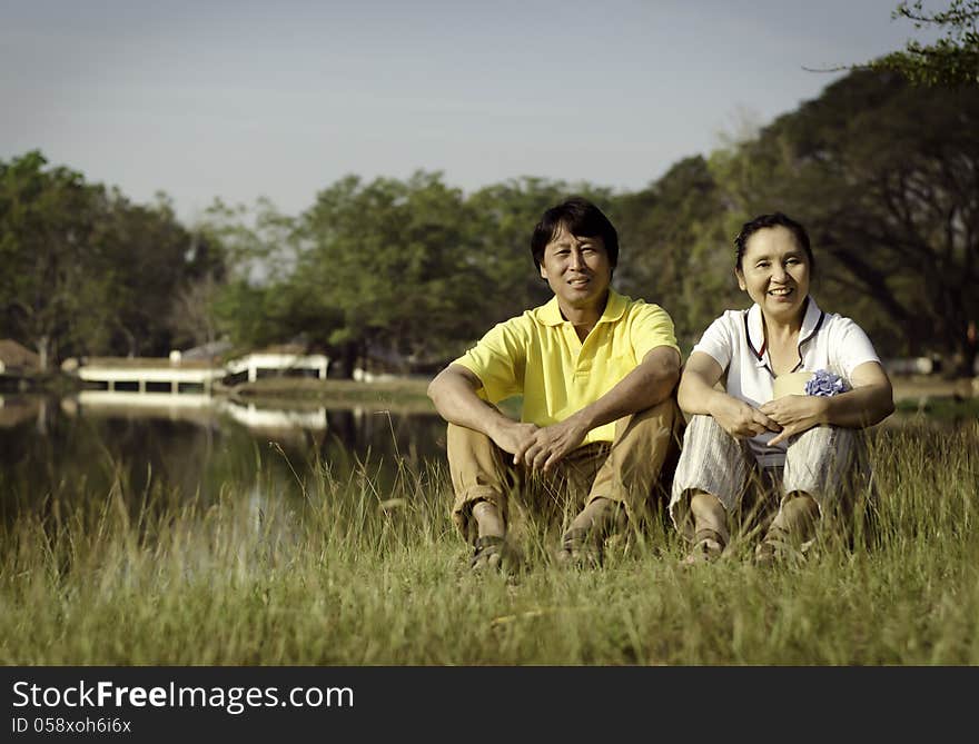 Portrait of beautiful couple sitting on ground in park