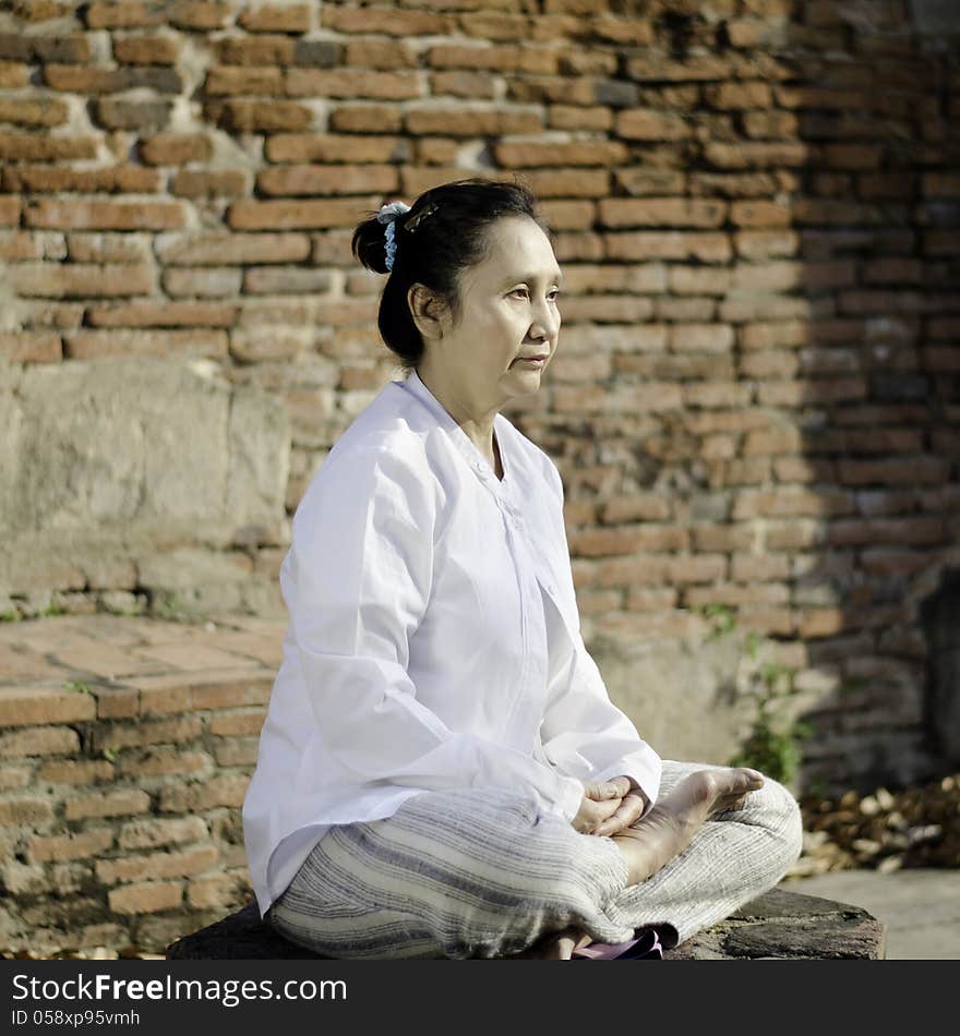 Asian woman meditating in ancient buddhist temple