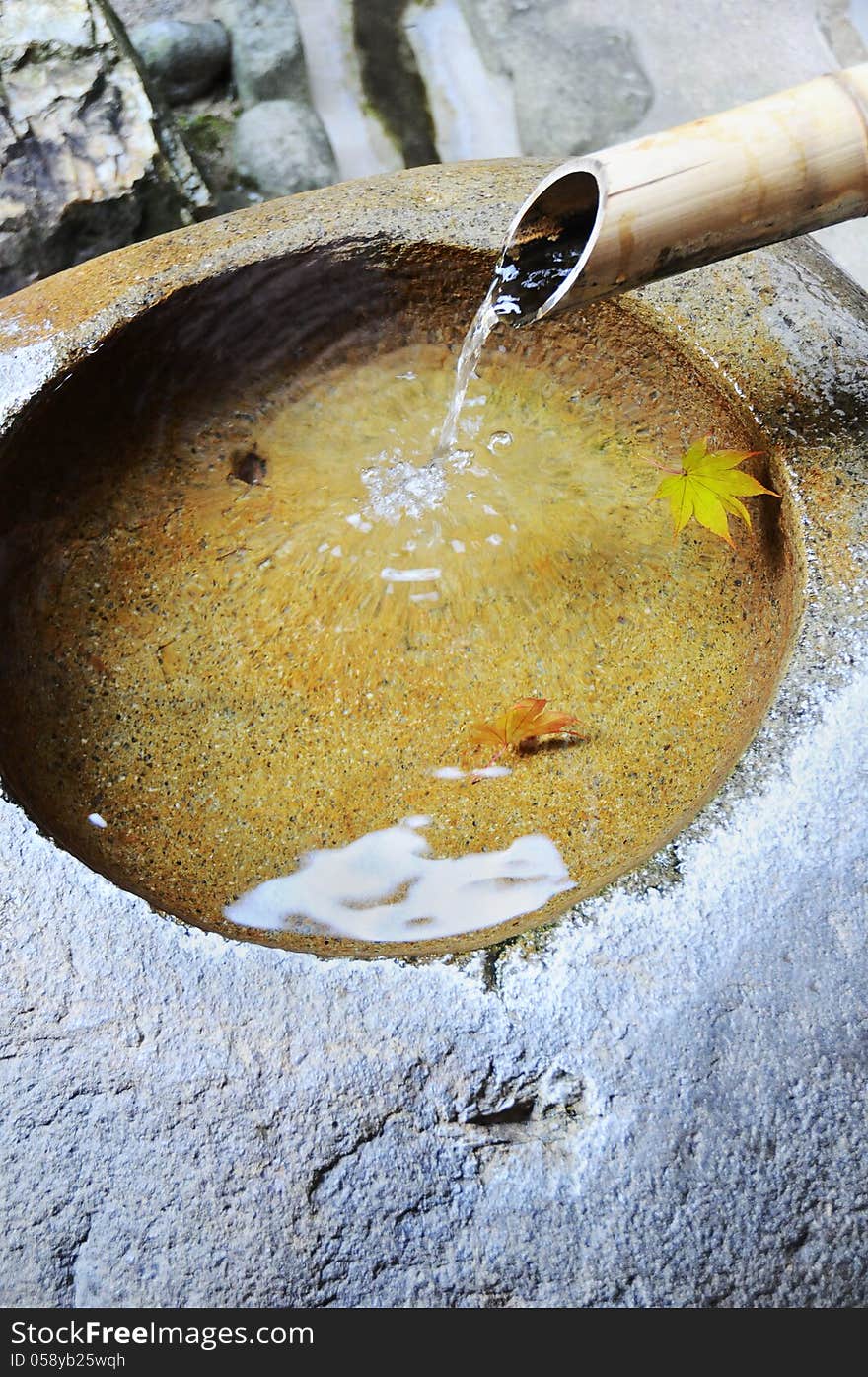 Bamboo tube and flowing water into the basin stone