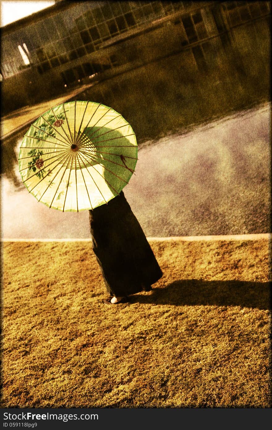 Girl with a parasol standing by the water