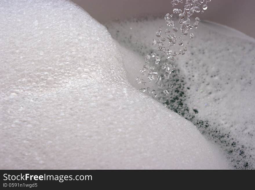 Flow of water droplets into bubbly / foamy bath water. Flow of water droplets into bubbly / foamy bath water