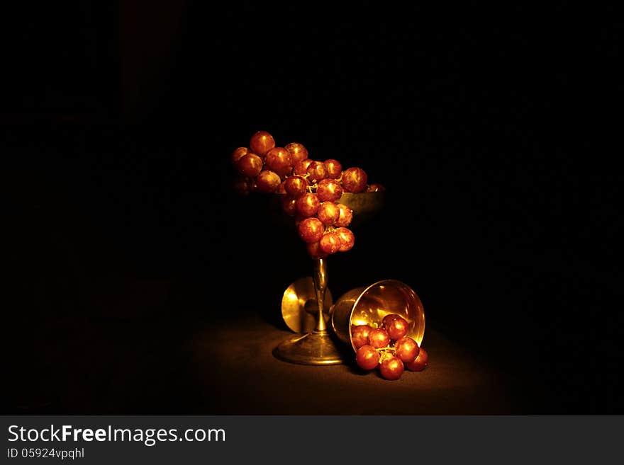 Red grapes in a tarnished silver goblet.