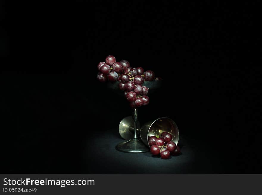 Red grapes in a tarnished silver goblet. Red grapes in a tarnished silver goblet.