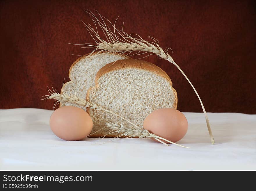 Brown bread and eggs surrounded by barley.