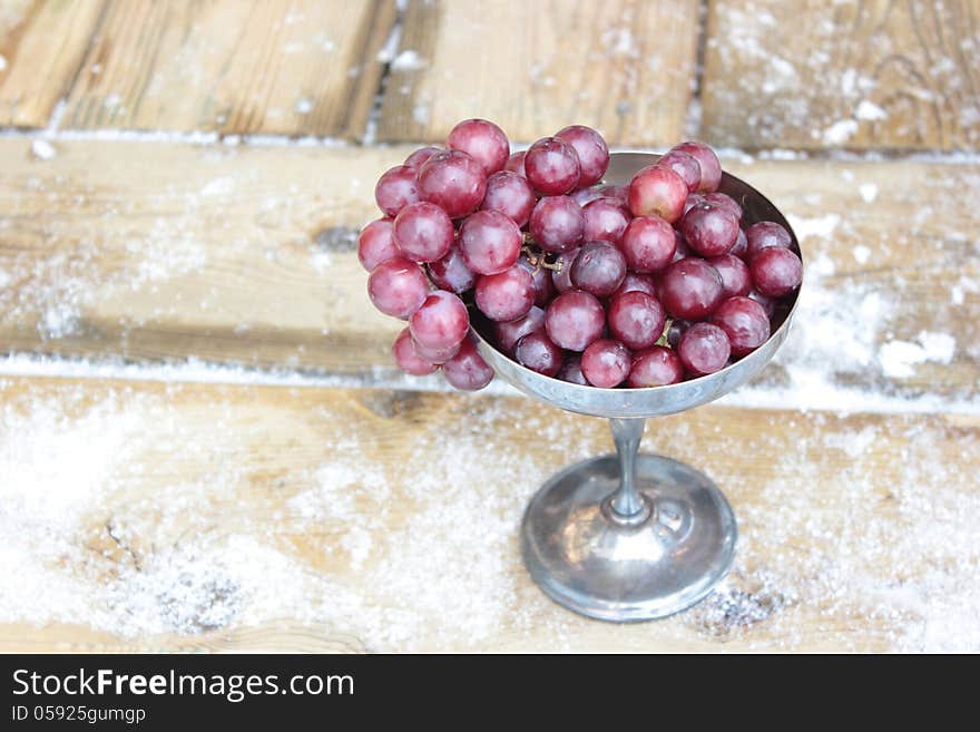 Red grapes in a tarnished silver goblet.