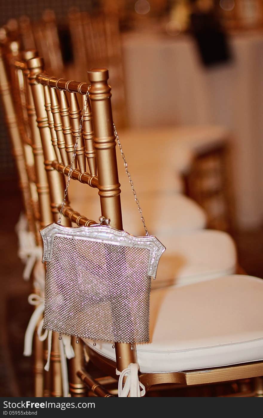 An elegant gold chair and silver purse at formal event.