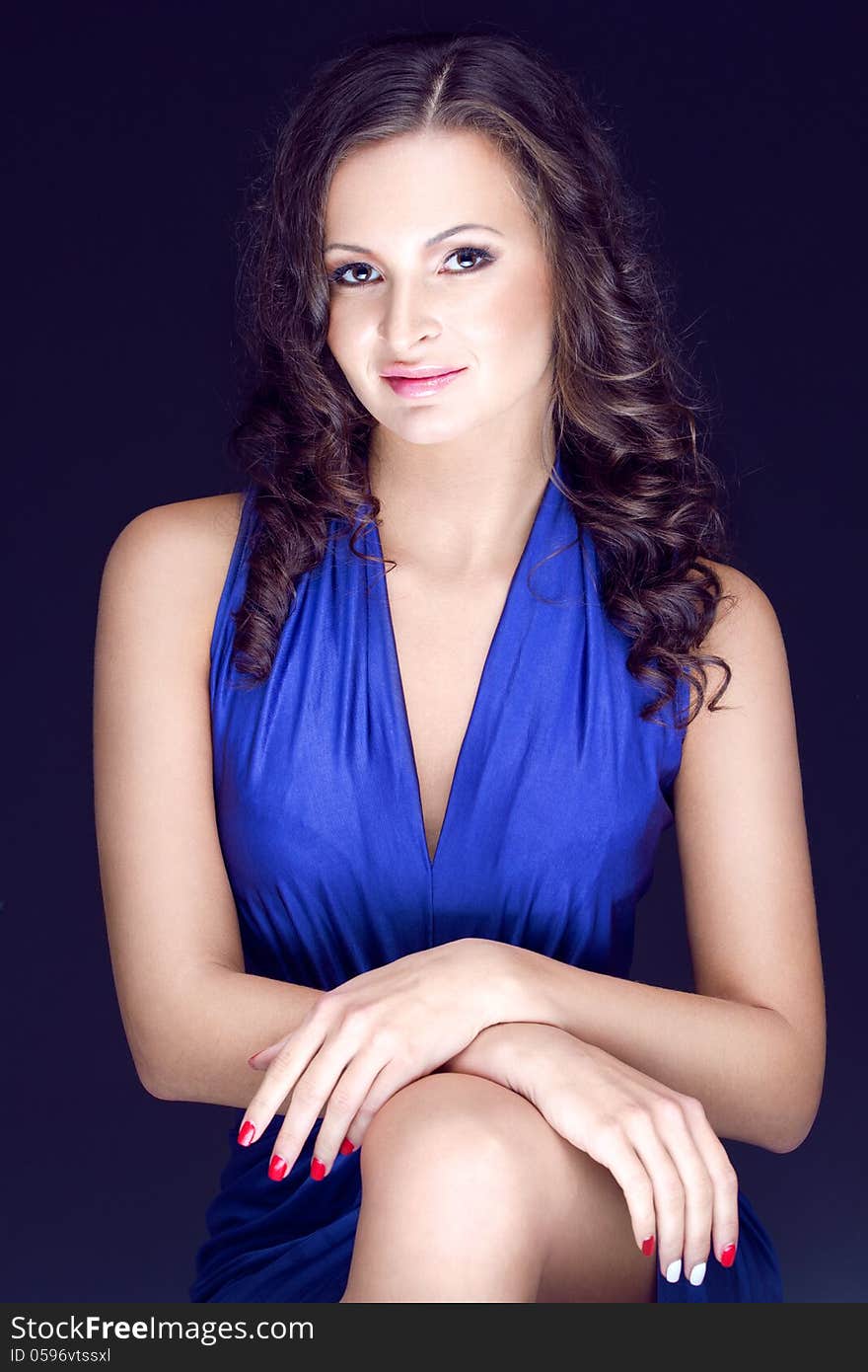 Young gorgeous brunette in blue silk dress posing in the studio. Young gorgeous brunette in blue silk dress posing in the studio