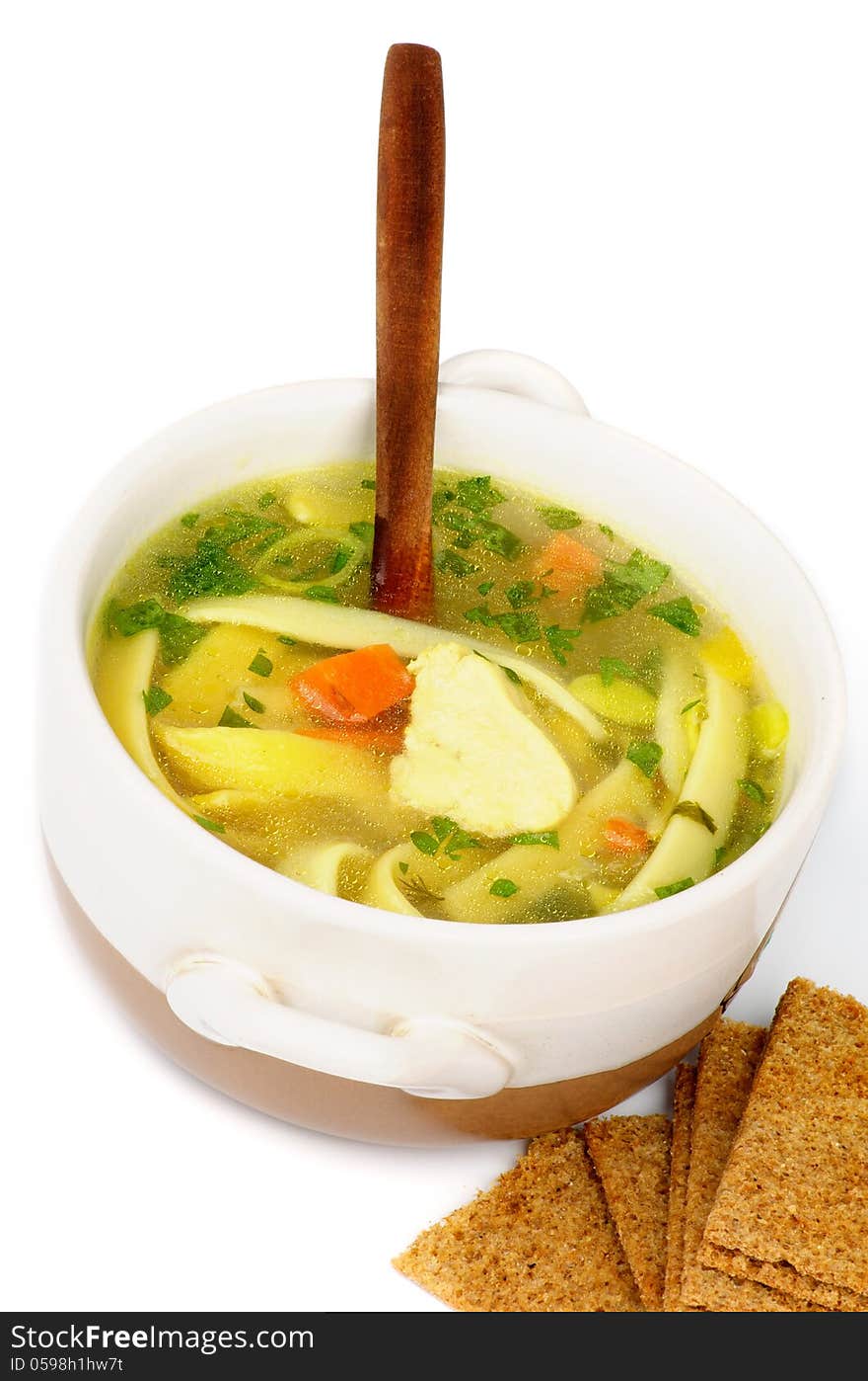 Chicken Noodle Soup with Parsley and Carrot in White Bowl with Wooden Spoon and Crispy Bread closeup on white background