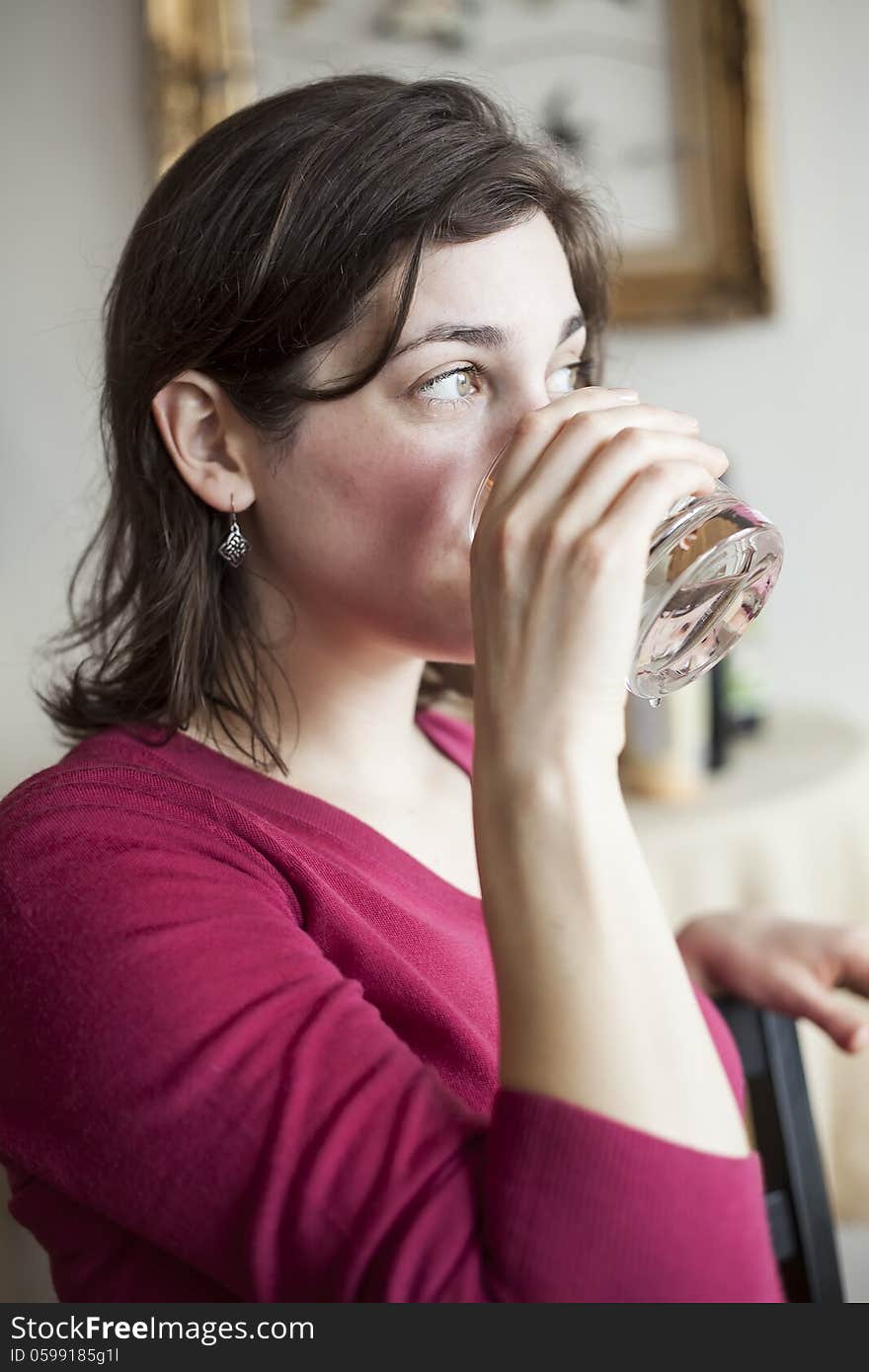 Beautiful young woman in a pink sweater drinks a glass of water. Beautiful young woman in a pink sweater drinks a glass of water.