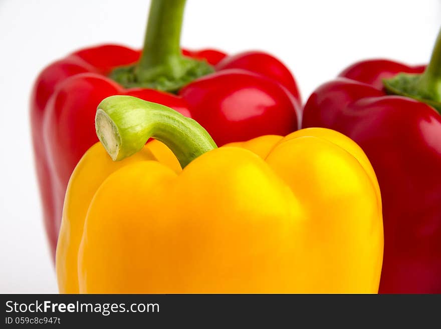 The picture shows 3 peppers in yellow and red. Tabletop with white background.