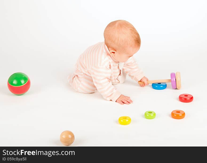 Happy baby playing with a toy pyramid on white background