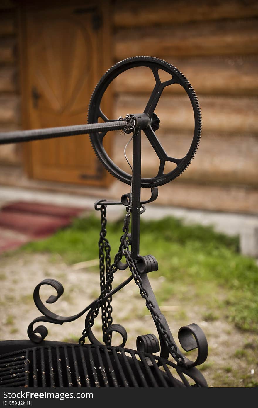 Close up of traditional barbecue mechanism in Polish mountains style, craftmanship. Nice wooden house background.