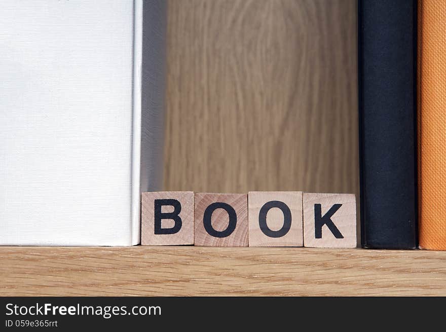 Books in a bookshelf with wooden cubes spelling book