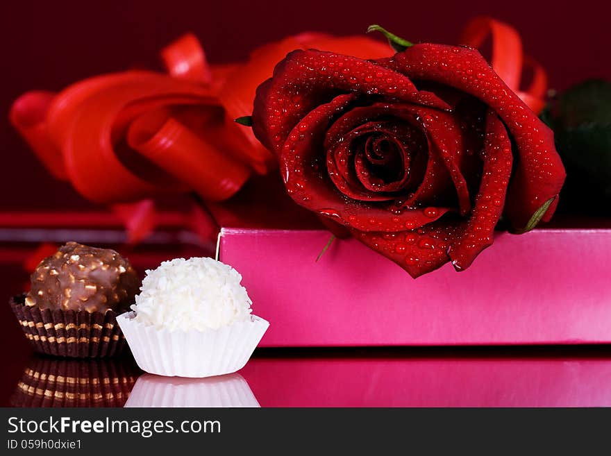 Beautiful red roses with chocolates on a red background. Beautiful red roses with chocolates on a red background