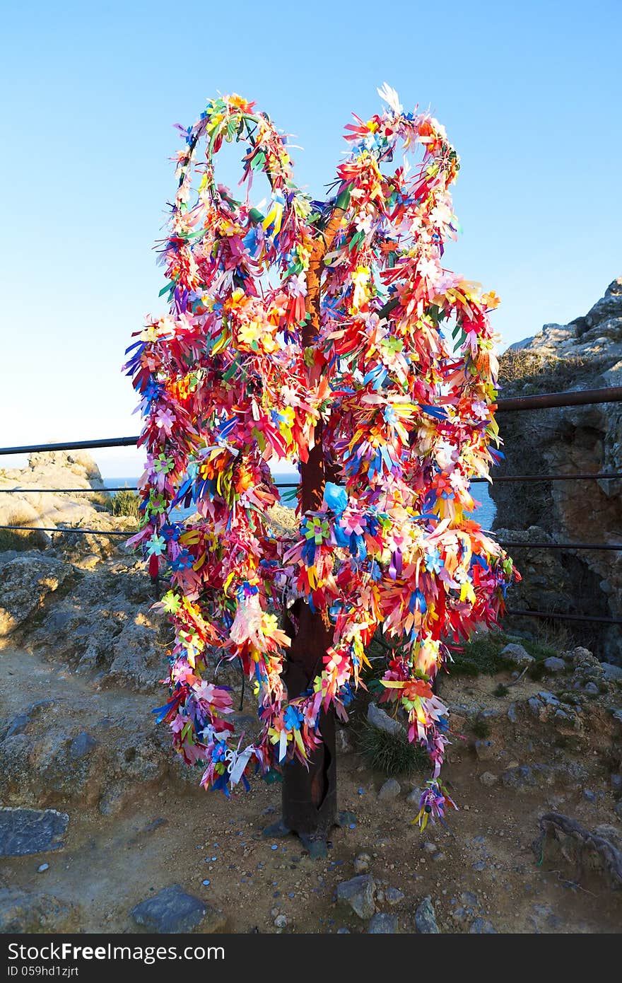 Wish tree decorated colored tape in mountains near sea