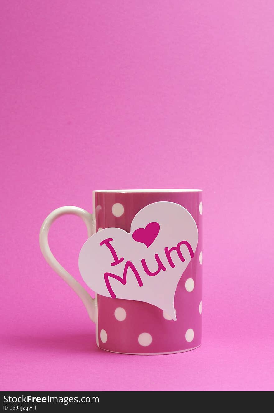 Pink polka dot coffee or tea mug with heart shape white gift tag with I Heart Love Mum for Mothers Day on pink background with copy space for your text here. Pink polka dot coffee or tea mug with heart shape white gift tag with I Heart Love Mum for Mothers Day on pink background with copy space for your text here.