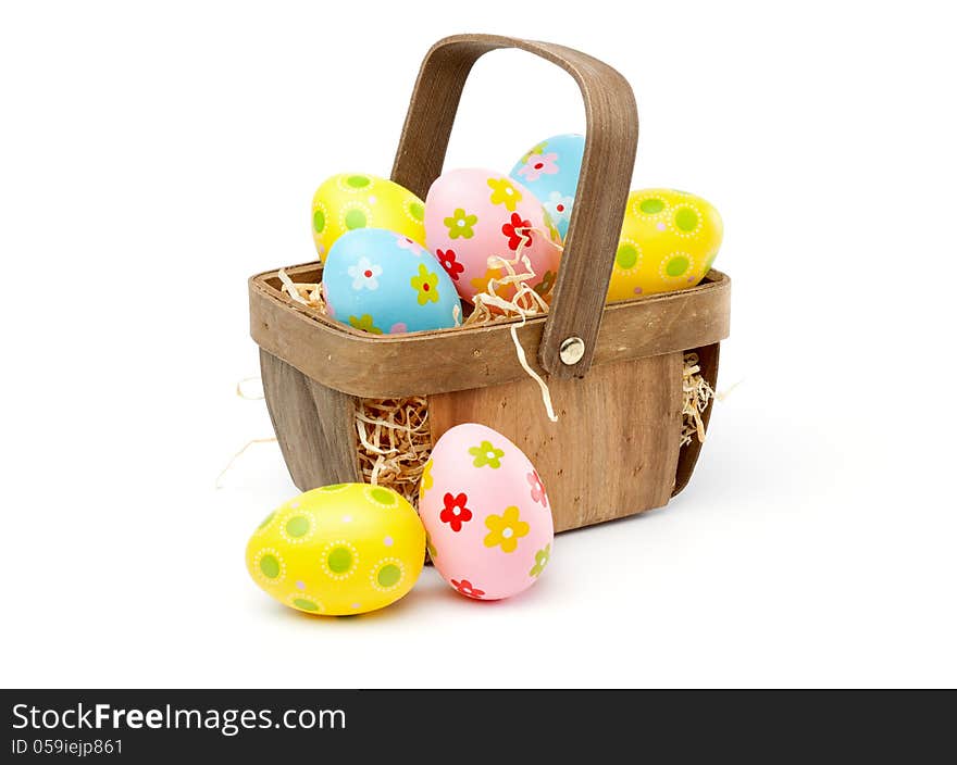 Painted, multi colored easter eggs in a basket, isolated on white background