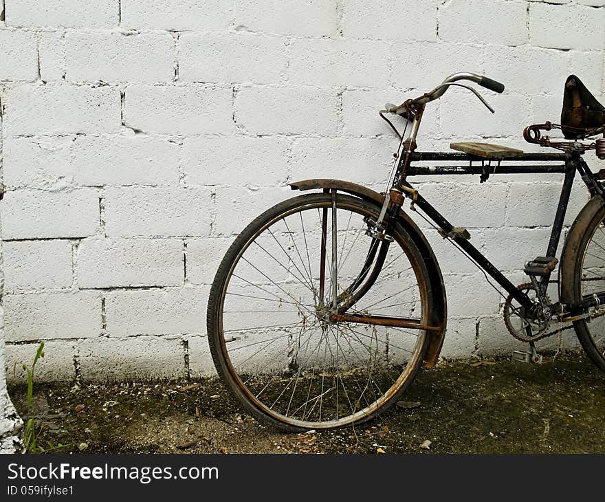 An old classic bike in front of white concrete wall. An old classic bike in front of white concrete wall