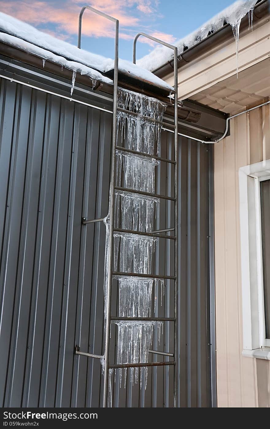 Dangerous step vertical ladder to the roof covered with icicles. Dangerous step vertical ladder to the roof covered with icicles