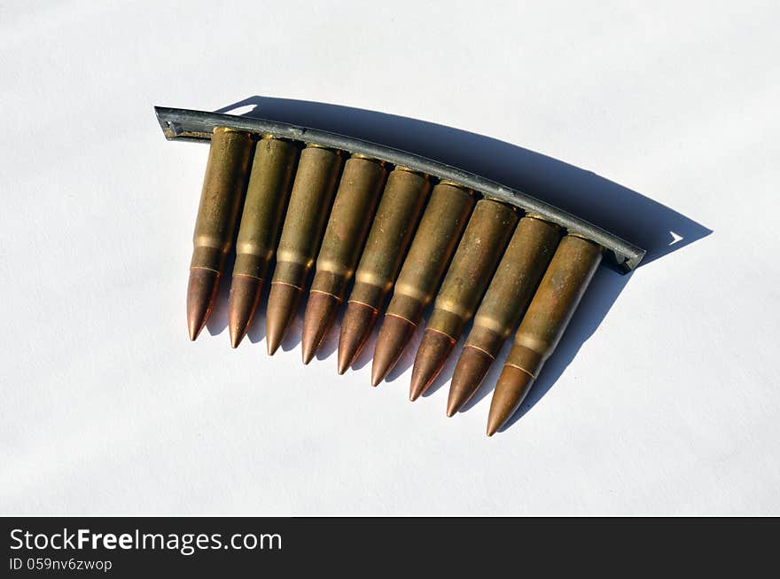 Bandoleer of machine gun bullets on white background in strong light