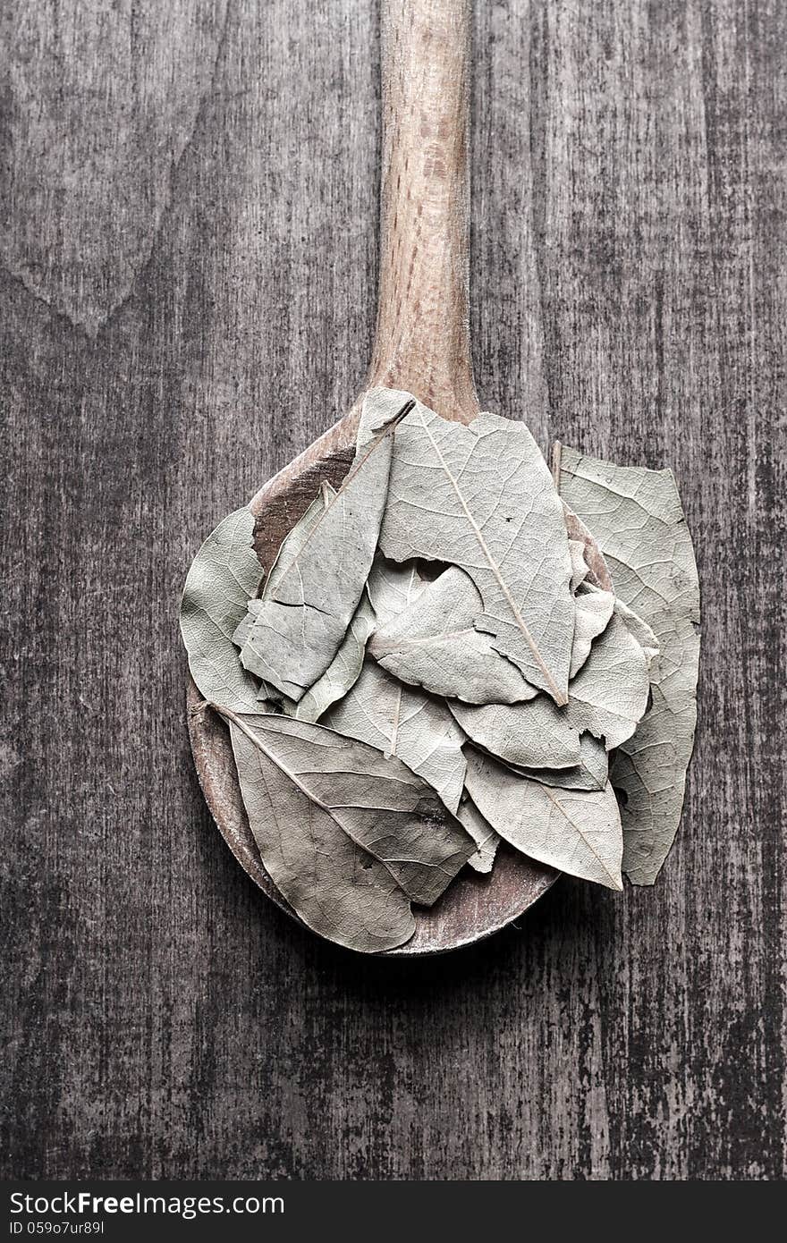 Top view of wooden spoon full of dried bay leaves