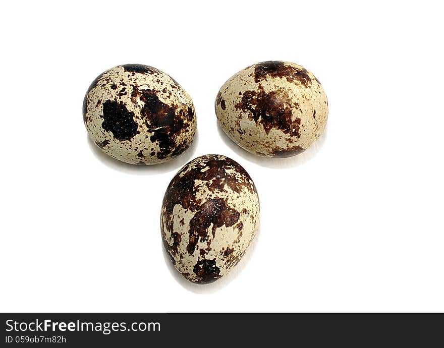 Three quail eggs on white background with light shadow