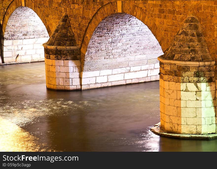 Old Stone Bridge Arch Over A River at night