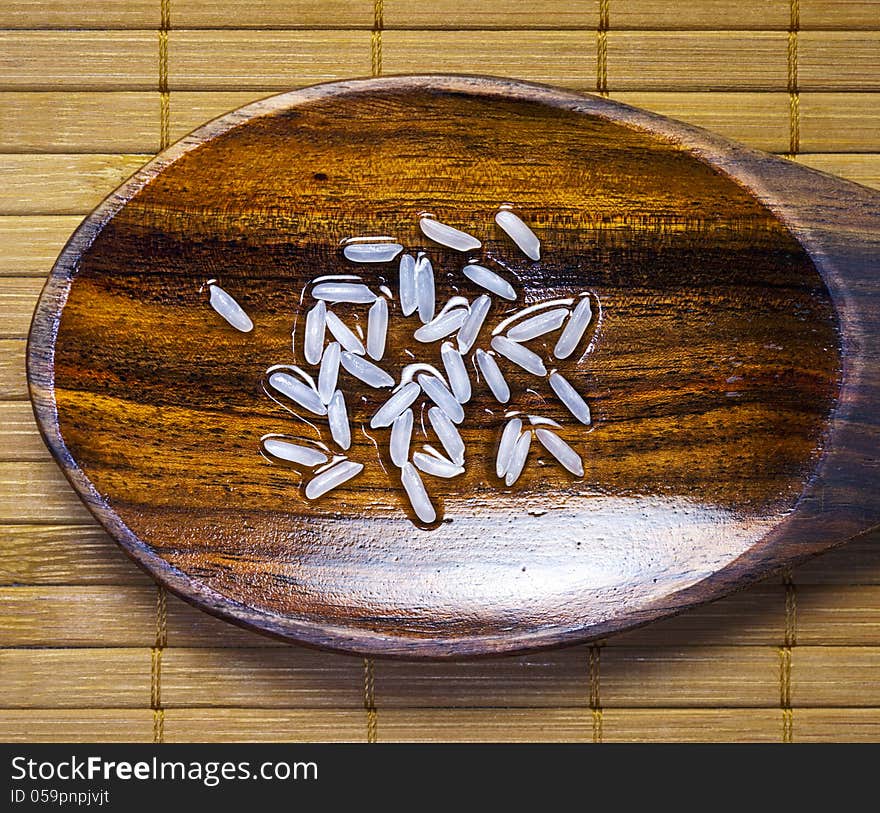 Grain of rice on wet wooden spoon