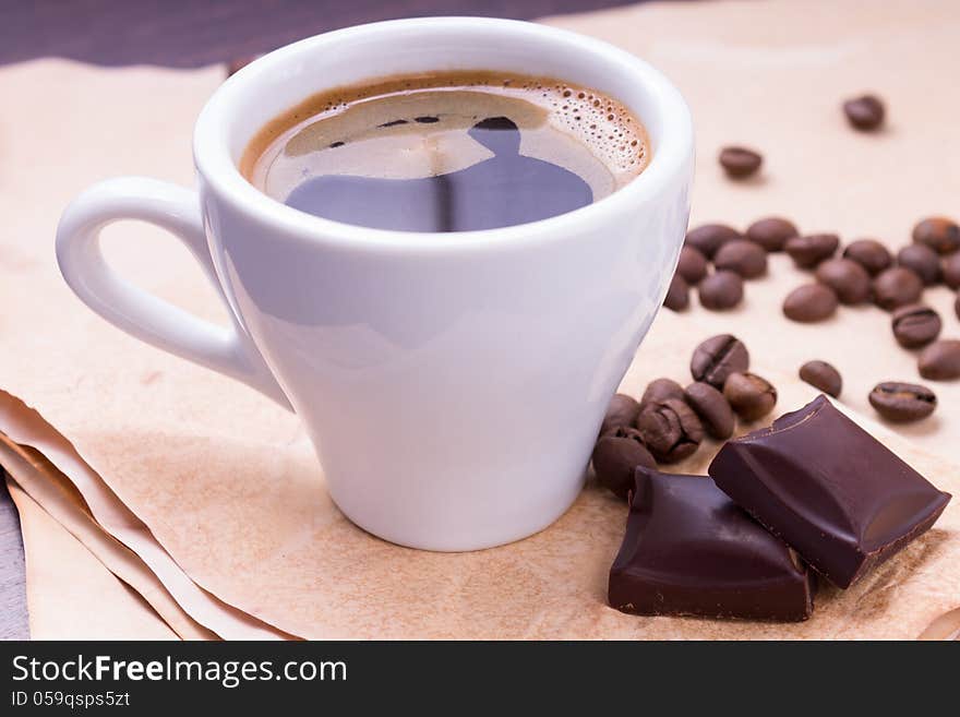 Cup of coffee and beans with chocolate on paper background